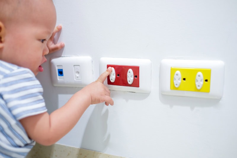 Electrical Safety Tips. Curious toddler baby boy plays with electric plug.